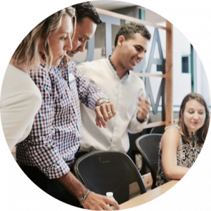 Business team collaborating around a laptop representing the Human Zone of the SoT AI Enterprise Reference Model -- where governance, adoption, enablement, and AI strategy and leadership determine whether AI delivers sustained business impact